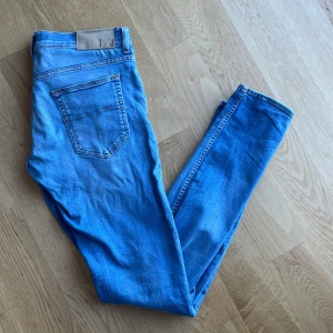 Blåa Tiger of Sweden jeans  - Snygga blå jeans från Tiger of Sweden i italienskt premiumdenim. Klassisk femficksdesign med knappgylf och bälteshällor. Perfekta för en stilren look.