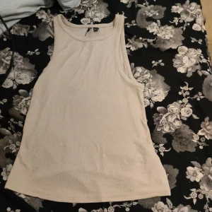 Beige ribbad linnetopp från Vero Moda - Säljer en stilren beige ribbad linnetopp från Vero Moda. Perfekt för varma dagar med sin ärmlösa design och mjuka material. Passar utmärkt till både jeans och kjol.