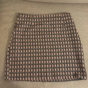 Ribbed kjol i rosa och svart - Kjol i rosa och svart med en klassisk design. Kjolen är kort och har en stilren passform