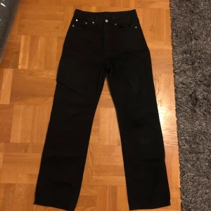 Svarta jeansbyxor - Svarta jeansbyxor från Weekday (Rowe) med hög midja och klassisk straight passform. Perfekta för en stilren look. Den har två fläck på framsidan och även en i backfickan (se bild). Färgen är lite washed out. Kan även hämtas på plats:) 