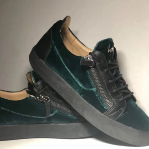 Gröna giuseppe zanottis - Snygga gröna giuseppe zanottis i sammet med svarta detaljer och dragkedja på sidan. Skorna har en svart sula och snörning framtill, vilket ger en stilren look. 7/10 skick, har en liten defekt p tån men syns knappt när man bär dem. var inte rädd för att fråga om minsta lila. är också öppen mot byten.