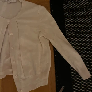 Vit kofta från French Connection - Säljer en stilren ljus rosa  kofta från French Connection. Koftan har långa ärmar och knappar framtill. Perfekt för lager-på-lager och passar till många olika outfits. Den är som en bolero fast med långa armar! Perfekt till våren 