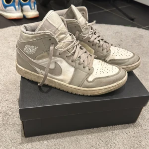 Air Jordan 1 mid Linen - Snygga Air Jordan 1 Linen med klassisk design och snörning. Skorna har en hög modell med sin ikonisk logga på sidan. Perfekta för en stilren look. Dessvärre finns det mycket tecken på användning och skorna är slitna på undersidan. Nypris 4000kr