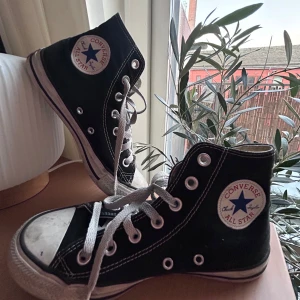 Svarta Converse All Star sneakers - 🪐Klassiska svarta Converse All Star sneakers i hög modell och vita snören. Skorna har den ikoniska logotypen på sidan och en vit gummisula. Perfekta för kommande vår och sommar!  🎀Använt skick, syns något på sulan 🎀