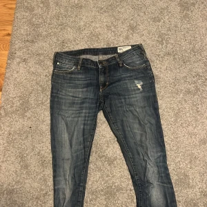 Blå jeans från Crocker - Säljer ett par blå skinny jeans från Crocker, modell Pep! De har en snygg slitning på ena benet och klassisk femficksdesign. Perfekta för en avslappnad stil.