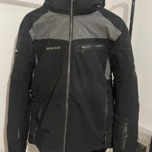 Svart och grå jacka från 8848 Altitude - Säljer en snygg svart och grå jacka från 8848 Altitude. Jackan har en dragkedja framtill och flera praktiska fickor med dragkedjor. Perfekt för kyligare dagar med sin stilrena design och funktionella detaljer.