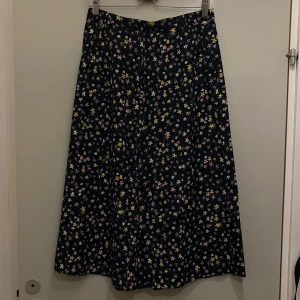Blommig kjol från Cappuccini - Ankellång kjol med flerfärgat småblommigt mönster. Är lågmidjad men jag har använt den med säkerhetsnål eller skärp som högmidjad, har hällor.                                                                                    Kolla gärna min profil, säljer mycket nu, allt i fint skick och till bra pris
