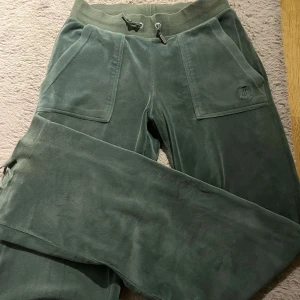Gröna mjukisbyxor från Juicy Couture - Säljer ett par gröna mjukisbyxor från Juicy Couture i storlek XS. Byxorna har en bekväm resårmidja med snörning och praktiska fickor framtill. Perfekta för en avslappnad stil. Bara att höra av sig vid frågor💕💕💕