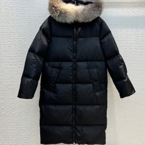 Svart dunjacka med päls från Moncler - Snygg och varm svart dunjacka från Moncler med en lyxig pälsdetalj på huvan. Jackan har en lång passform och är perfekt för kalla vinterdagar. Den har en dragkedja framtill och praktiska fickor.
