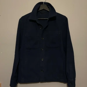 Donce de la sense overshirt - Snygg mörkblå overshirt från Donce de la sense med knappar framtill och två bröstfickor. Jackan har en klassisk krage och långa ärmar. Perfekt för en stilren look.