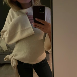 Vit tröja med knytband - Säljer en stilren vit tröja med långa lite vidare ärmar och ett snyggt knytband i sidan. Perfekt för en avslappnad look. 