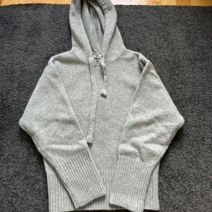 Grå stickad hoodie - Säljer min jättesnygga gråa stickade hoodie som är använd 1 gång och ser helt ny ut och passar perfekt nu till vintern!!