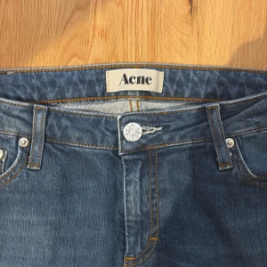 Blå jeans från Acne - Säljer ett par snygga blå jeans från Acne i storlek 29/32. De har en klassisk femficksdesign med en knapp och dragkedja framtill. Jeansen är i en slim stil och har en skön passform. Fickorna är dock små.
