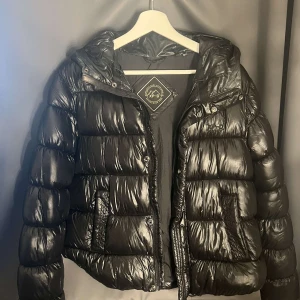 Svart pufferjacka från Superdry - Säljer en snygg svart pufferjacka från superdry som jag inte har användning för längre men är varm och skön nu till höst och vintern. Syns knappt att den är använd men är en liten skråma på ena armen från butik.