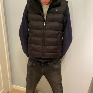 Gant väst - Snygg svart dunväst från Gant med dragkedja framtill. Perfekt för lager-på-lager under kyliga dagar. Västen har en klassisk design med quiltade paneler och en diskret logga på bröstet. storlek 15 år 170. Använd ett fåtal gånger.