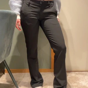 Svarta kostymbyxor från BikBok - Snygga svarta kostymbyxor från BikBok med en elegant passform. Byxorna har en klassisk design med dragkedja och knapp framtill. Perfekta för en stilren look.