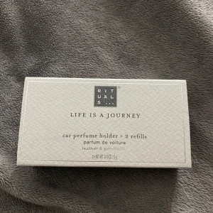 Bilparfymhållare med 2 refiller från Rituals - Säljer en bilparfymhållare från Rituals med två refiller i doften läder och patchouli. Förpackningen är elegant och stilren, perfekt för att fräscha upp bilen med en lyxig doftupplevelse. Enkel att använda och byta ut refillerna.