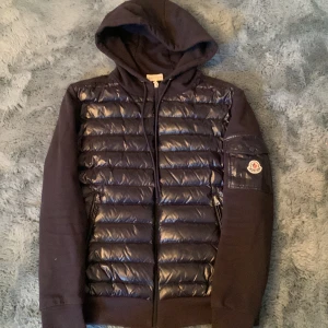 Moncler cardigan maglia con cappucio  - Snygg marinblå jacka från Moncler med huva och dragkedja. Dun material på framsidan. Jackan är drygt 3 år gammal så därav priset och skadorna på jackan. Riktigt bra jacka för små kylig vår och höst dagar, väldigt stilren design. Priset är inte hugget i sten och vid snabb affär sänks priset naturligtvis 