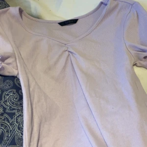 fin ljulila tröja - Säljer en ljuslila ribbad topp från Shein med korta ärmar och en fin rynkdetalj framtill. Perfekt för en avslappnad stil. 💜