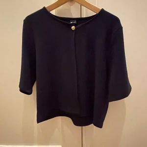 Mörkblå tröja från Gina Tricot - Säljer en stilren mörkblå tröja från Gina Tricot med trekvartsärmar och en dekorativ knapp framtill. Perfekt för en elegant och avslappnad look. Storlek XL men passar mig som vanligtvis har s/m💕