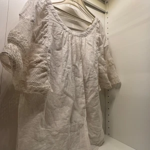 Vit blus med spetsdetaljer - Charmig vit blus med vackra spetsdetaljer på ärmarna. Blusen har en lös passform och trekvartsärmar som ger en romantisk känsla. Perfekt för en avslappnad och stilfull look.