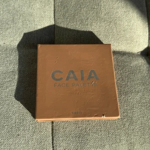 Face Palette från CAIA - Snygg face palette från CAIA med fyra olika nyanser: contour, blush, bronzer och highlighter. Perfekt för att skapa en komplett look. Paletten har en inbyggd spegel för enkel applicering.