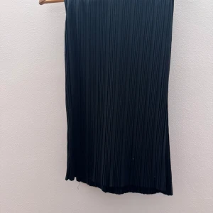 Svarta over size byxor - Elegant svart over, size byxor som passar perfekt för en stilren look. Kjolen har en klassisk design med plisserade detaljer som ger en fin rörelse. Perfekt för att matcha med olika toppar och accessoarer.