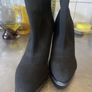 Svarta boots med klack - Snygga svarta boots med hög klack och spetsig tå. Skorna har en stickad textur som ger ett modernt och stilrent intryck. Perfekta för att lyfta vilken outfit som helst.