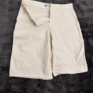 Vita jorts från Zara - Snygga vita/beiga jorts från Zara i en klassisk design. De  har en stilren look som passar perfekt för varma dagar. Tillverkade i ett bekvämt material som ger en skön passform.