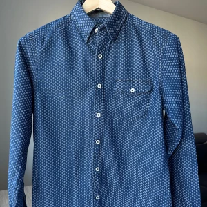 East West blå jeansskjorta slim fit, storlek S - Denimskjorta från East West. Slim fit, storlek S. 100% bomull. Fint skick, blekta armbågar. Dold button down. Jag säljer många skjortor i samma storlek, kolla gärna på mina övriga annonser för att skapa ett paket. Axelbredd: 43 cm Längd: 70 cm  Casual skjorta, smart.