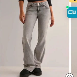 Grå bootcut jeans - Snygga grå bootcut jeans med låg midja och klassisk femficksdesign. Jeansen har en diskret tvättad look och dekorativa sömmar på bakfickorna. Perfekta för en avslappnad stil.