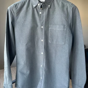 Homebound oxfordskjorta gråblå skjorta, storlek S - Gråblå oxfordskjorta från Homebound. Slim fit, storlek S. 100% bomull. Mycket fint skick. Button down. Jag säljer många skjortor i samma storlek, kolla gärna på mina övriga annonser för att skapa ett paket. Axelbredd: 42 cm Längd: 72 cm  Casual skjorta, smart, oxford.