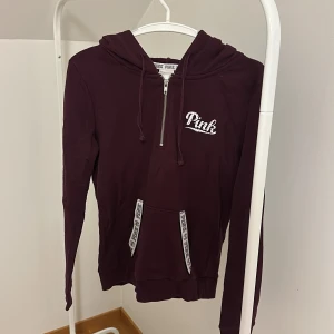 Vinröd hoodie från Victoria's Secret Pink - Säljer en vinröd hoodie från Victoria's Secret Pink med dragkedja och huva. Tröjan har långa ärmar och en praktisk ficka framtill. Perfekt för en avslappnad stil. 💜