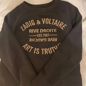 Svart tröja från Zadig & Voltaire - Snygg svart tröja från Zadig & Voltaire i XS, med guldtryck på framsidan. Tröjan har långa ärmar och rund halsringning. 
