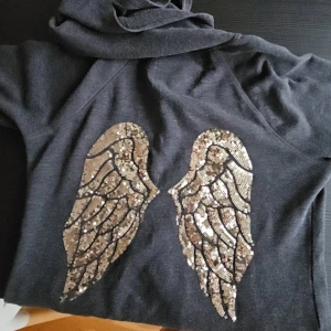 Victoria secret hoodie - En jätte fin grå Victoria's secret hoodie med gludiga glitter vingar på ryggen, använd några gånger men fortfarande i fint skick. Storlek xs! - normal i storleken 💞
