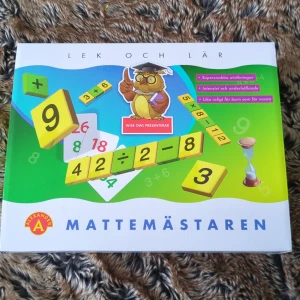 Mattemästaren Lek och Lär - Mattemästaren från Alexander är ett pedagogiskt spel för att lära sig matematik på ett roligt sätt. Innehåller färgglada nummerbrickor, en timglas och en gul påse för förvaring. Perfekt för både barn och vuxna som vill utmana sina matematiska färdigheter.