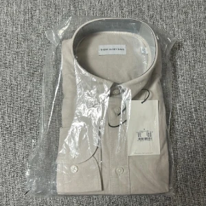 Beige skjorta från These Glory Days - Snygg beige kortärmad skjorta från These Glory Days. Skjortan har en klassisk design med knappar framtill och en stilren krage. Perfekt för en stilren look.