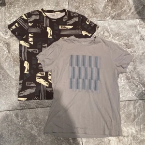Två t-shirts från Dressmann - Säljer två t-shirts från Dressmann i storlek M. Den ena är brun med ett abstrakt mönster i beige och grått. Den andra är grå med ett subtilt randigt mönster i blått. Perfekta för en avslappnad stil. Nyskick, knappt använda.