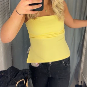 Gul tubtopp - Snygg gul tubtopp perfekt för sommardagar. Den är ärmlös och har en enkel design som gör den lätt att matcha med olika outfits.