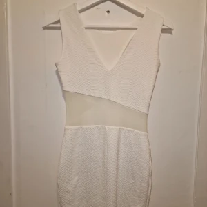 Vit klänning från Miss Selfridge - Snygg vit klänning med ormskinnsmönster och en transparent detalj i midjan som ger en modern touch. Perfekt för en stilren look!