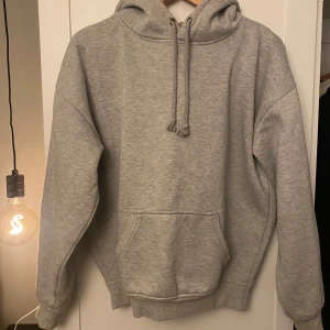 Grå hoodie från Bik Bok - Säljer en grå hoodie från Bik Bok i storlek XS. Den har en stor ficka framtill och justerbar huva.