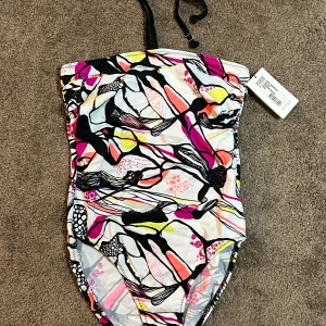 Färgglad baddräkt från Röhnisch - NY Snygg och färgglad baddräkt från Röhnisch med abstrakt mönster i rosa, gul och svart. Justerbara axelband och en stilren design som passar perfekt för stranden.