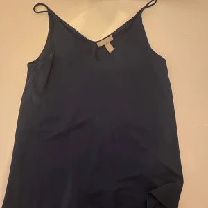 Mörkblå linnetopp från H&M - Säljer en stilren mörkblå linnetopp från H&M. Toppen har en v-ringad design och smala axelband, perfekt för varma dagar. Den är tillverkad i ett mjukt och bekvämt material som ger en skön passform. Har bara används en gång för jag har för mycket kläder💞