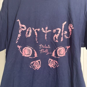 melanie martinez portals t-shirt - en mörkblå/marinblå t-shirt med rosa tryck från melanies album portals. framsidan har texten ”portals” med fjärilsmotiv, medan baksidan är fylld med olika lyrics från albumet. EJ OFFICIELL MERCH, den är tryckt med ett motiv som köptes på etsy. enkel men skön kvalitet, i storlek L. använd gärna köp nu om intresserad! :D