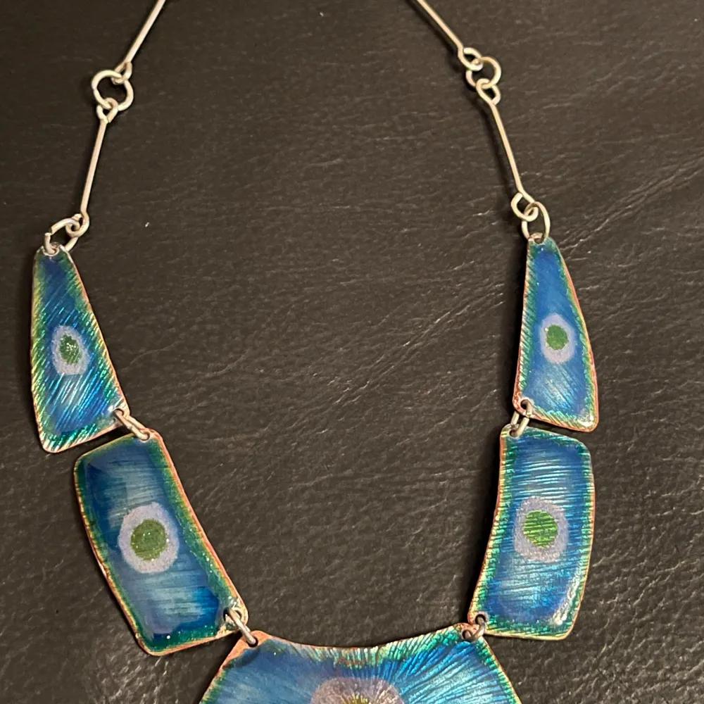 Säljer ett unikt vintage halsband med stora blå emaljerade plattor i abstrakt design. Plattorna har en vacker blå färg med cirkulära mönster i grönt och vitt. Halsbandet är handgjort och signerat på baksidan.. Asusteet.