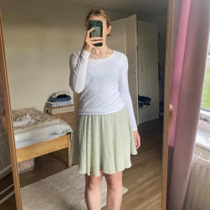 Ljusgrön kjol NA-KD - Säljer en superfin mintgrön kjol från NA-KD med ett blommigt(?) mönster. Det finns en tråddragning som syns på bilden, men den är väldigt liten och märks knappt när man har den på sig. Sista bilden visar bara dragkedja och metallgrej för att öppna/stänga.