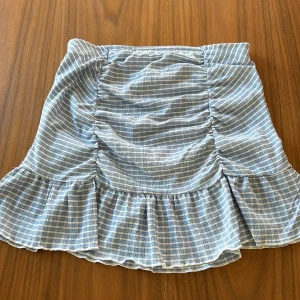 Randig kjol från Gina Tricot - Säljer en superfin randig kjol från Gina Tricot i storlek M. Kjolen har en söt volangdetalj längst ner och är perfekt för sommardagar. Den är i ett lätt och luftigt material, vilket gör den bekväm att bära hela dagen. Passar perfekt till både vardag och fest!