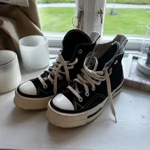 Säljer ett par klassiska svarta Converse All Star sneakers i hög modell. De har vita snören och en vit sula med svart rand. Perfekta för en avslappnad stil och passar till nästan allt. Använda 1 gång så i väldigt bra skick!