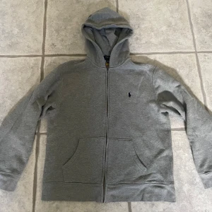 Polo ralph lauren hoodie  - Väldigt fin ralph lauren hoodie i nästan nyskick. Köptes för cirka 1 år sedan men har knappt använts då den blivit för liten för mig. Finns inga hål/fläckar eller liknande, fler bilder kan ordnas!  