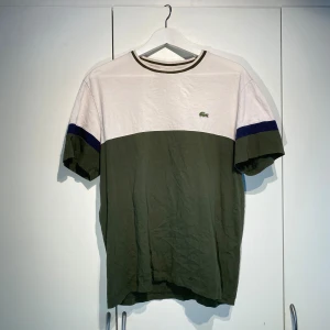 Lacoste bone/grön T-shirt - Hej, säljer en schysst T-shirt från Lacoste i bone & khaki färg. Stilren & lätt att styela. Storlek L och TTS. Välanvänd men i dugligt skick. Ikoniska och klassiska krokodilen. Köpt i Italien för 850kr. Pris kan diskuteras. Hörs i DM!